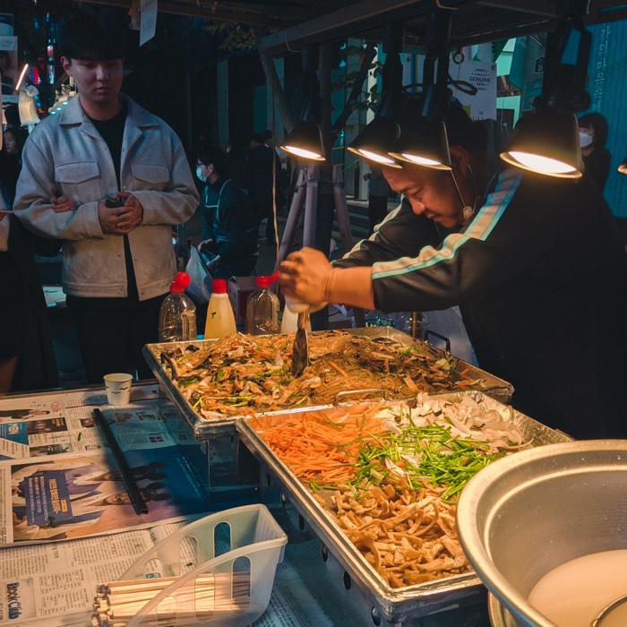 Street food vendor cooking under warm lamps at a night market stall