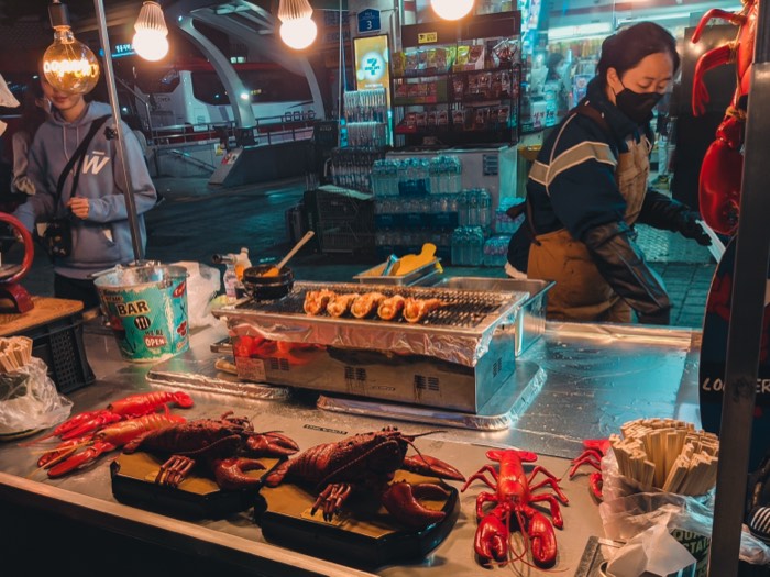 Bright red lobster tails laid out on ice at a night market seafood stall